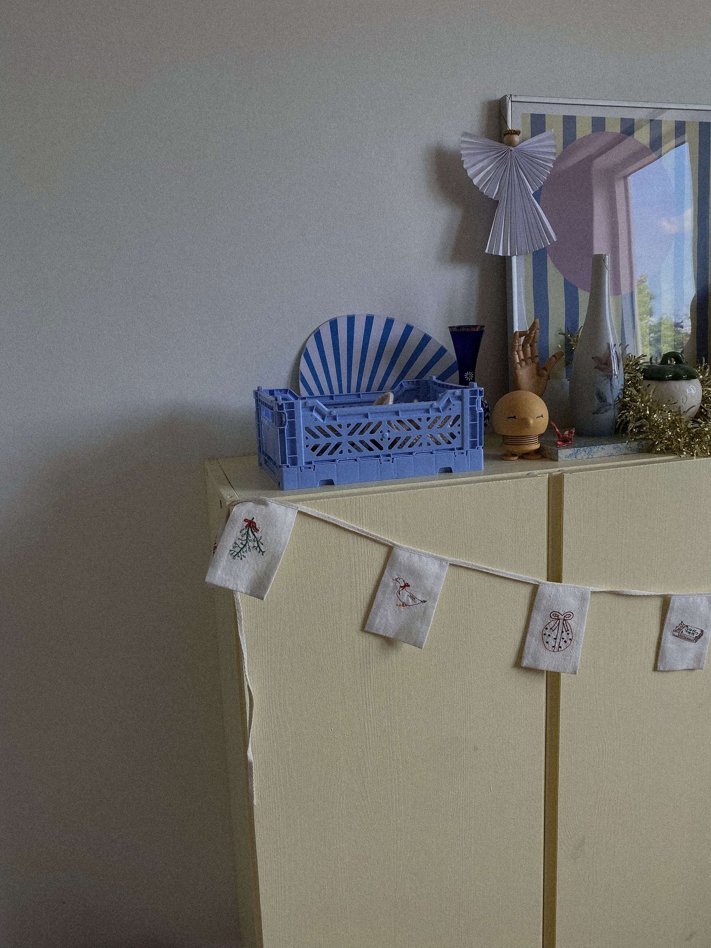 Guirlande med fine broderede detaljer hænger smukt over et skab i julepyntet hjem