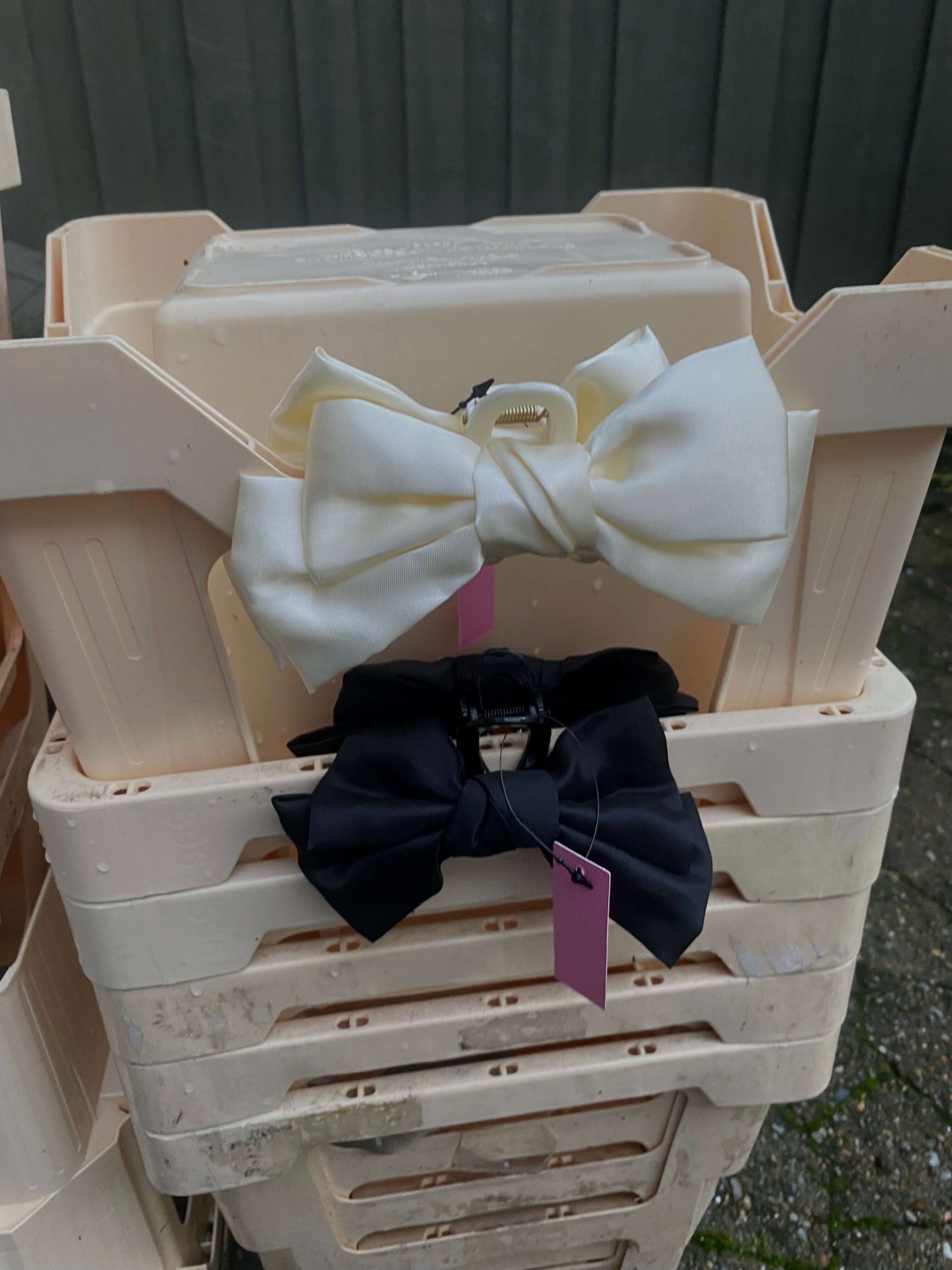 Bow Claw hårklemme i sort og creme, vist i opbevaringskurv – elegant håraccessory.