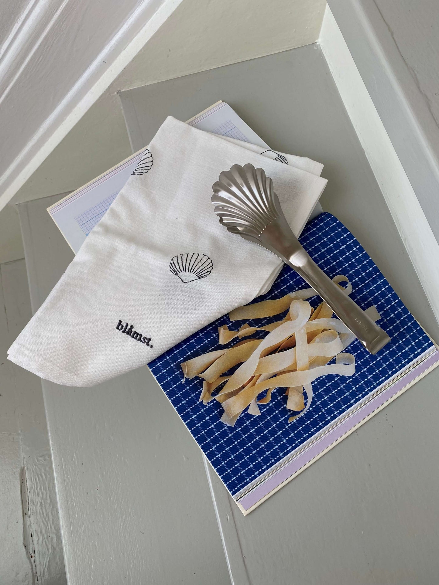 Blåmst pastatang i rustfrit stål – elegant muslingeformet tang til servering af pasta og salater.