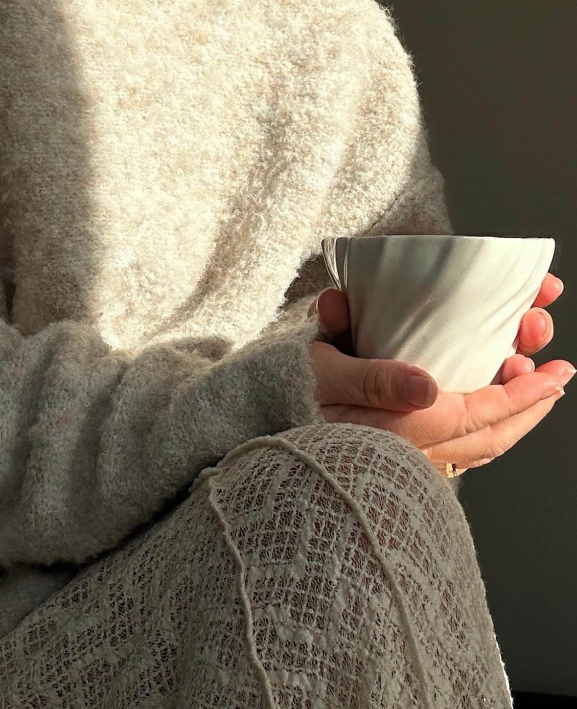 Kvinde nyder kaffe i tidevandskop på en solrig efterårsdag.