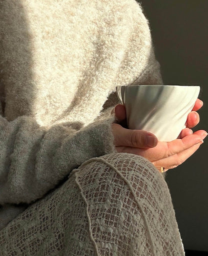 Kvinde nyder kaffe i tidevandskop på en solrig efterårsdag.