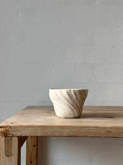 Tidevandskop i spættet porcelæn placeret på en træbordplade.