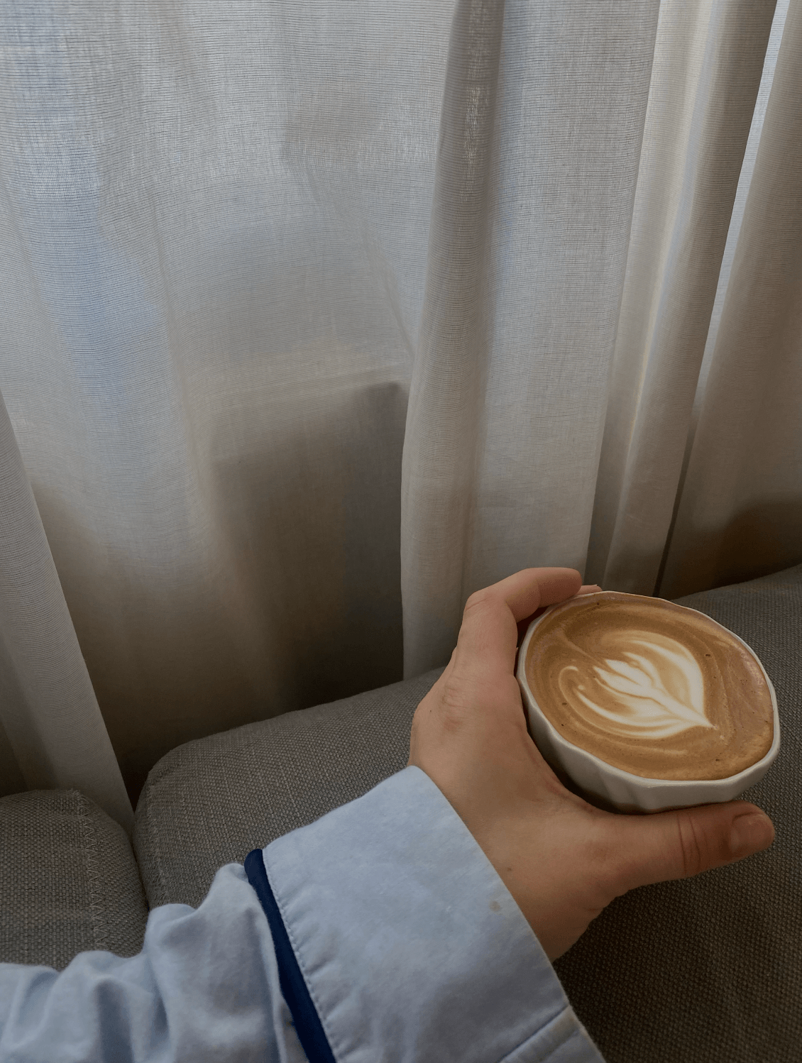 Hånd, der holder tidevandskoppen med skummende kaffe.