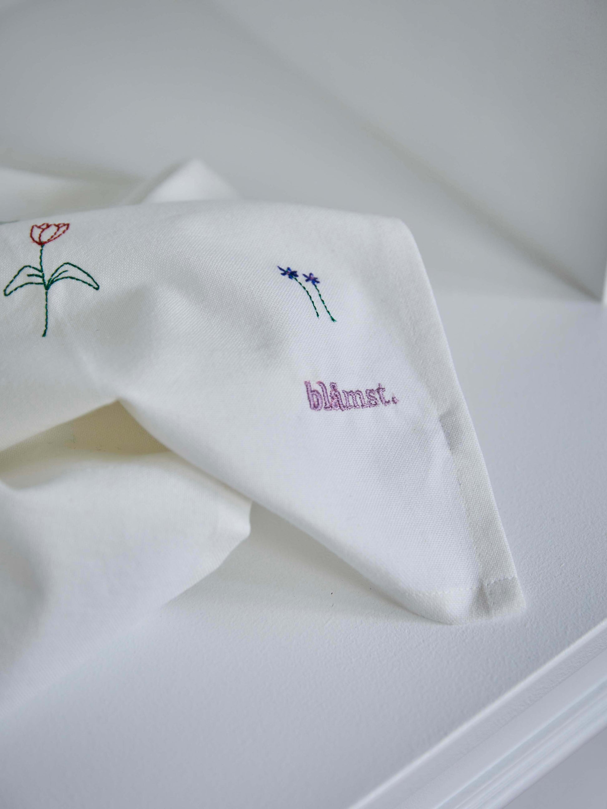 Nærbillede af Flower viskestykke fra Blåmst – broderede blå og røde blomster på blødt, absorberende bomuld."