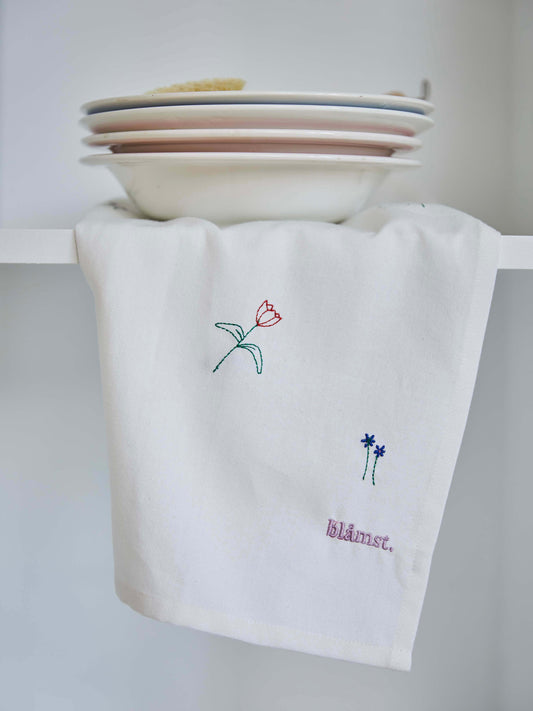 Blåmst Flower viskestykke med minimalistiske broderede markblomster og logo, skabt i GOTS-certificeret bomuld.