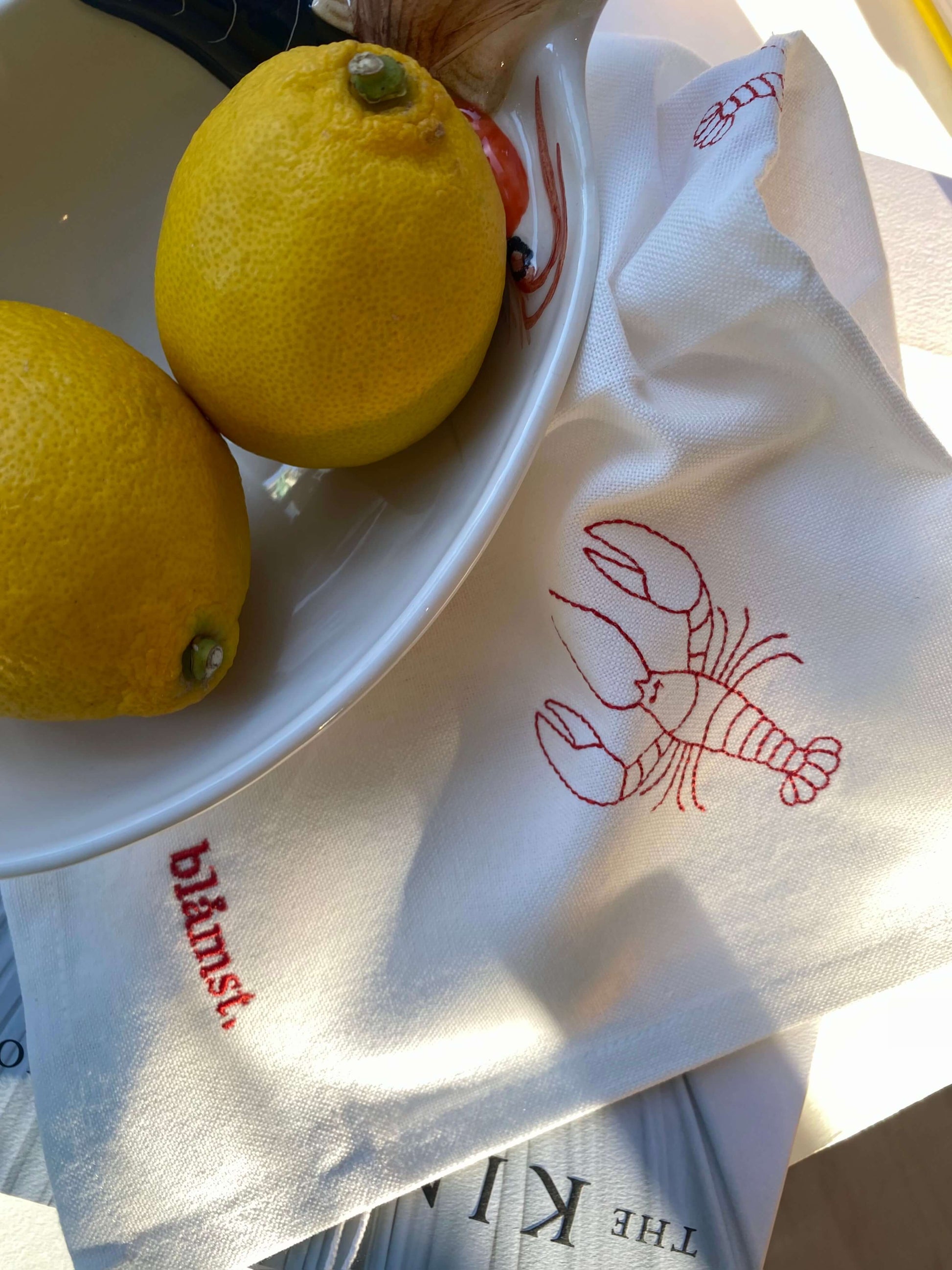 Nærbillede af hummer broderi på stofserviet med citron som dekoration