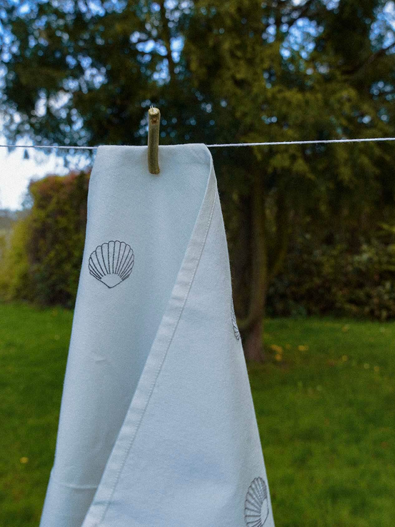 Detaljeret broderi på Musling Viskestykke – håndtegnede muslingemønstre broderet i fine sting, der giver viskestykket et unikt og organisk udtryk.